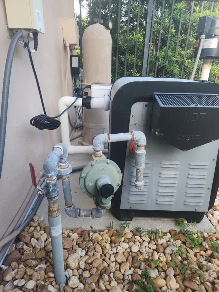A gas pool heater on a Boca Raton equipment pad being assessed during a Florida's Best Pools heater diagnostic visit