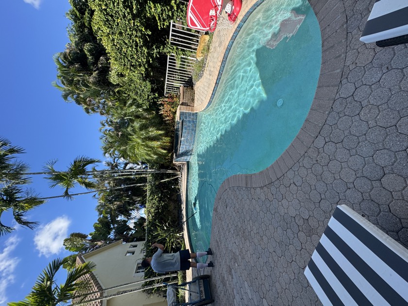 Florida's Best Pools technician emptying a debris-packed skimmer basket during a weekly South Florida pool service visit