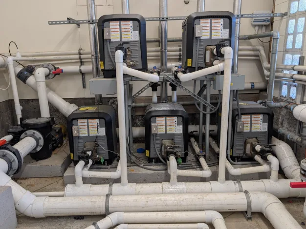 Chlorine and acid feeders and crocs on a South Florida commercial pool equipment pad