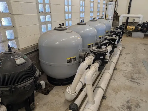 Chlorine and acid crocs and chemical feeders on a commercial pool equipment pad in South Florida