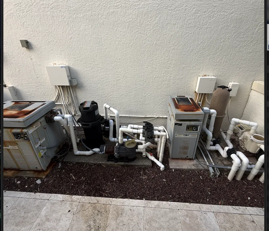 A gas pool heater with heavy rust and corrosion on the cabinet and burner tray — the visible result of years of unbalanced water chemistry and salt air on a South Florida pad