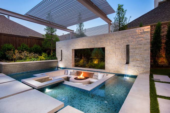 Hotel-grade pool design in a South Florida backyard — rectangular geometry, glass-tile waterline, tanning ledge, and integrated spa, exactly the hospitality-spec elements that translate cleanly to residential
