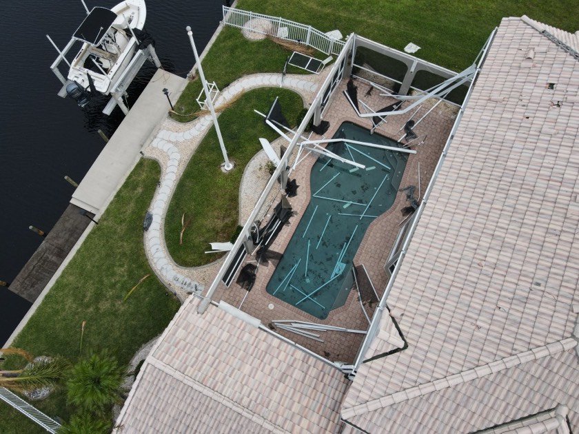 South Florida pool filled with storm debris and a damaged screen enclosure after a hurricane