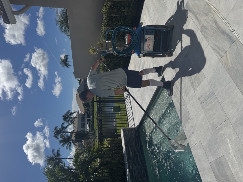 Florida's Best Pools technician brushing and cleaning a South Florida pool on a weekly route in Boca Raton